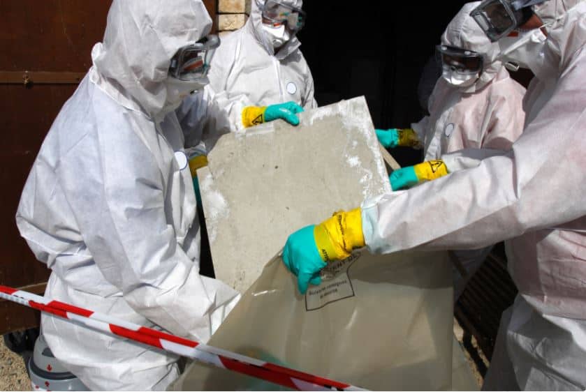 men in protective gear removing asbestos from a job site